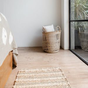 Teppich Wasserhyazinthe vor Bett mit Wäschekorb geflochten